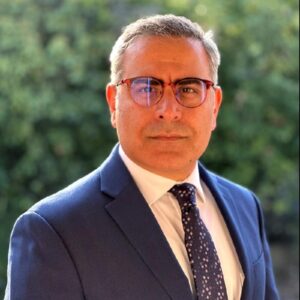 Hossein Ghiasi wearing a suit in front of a background of trees