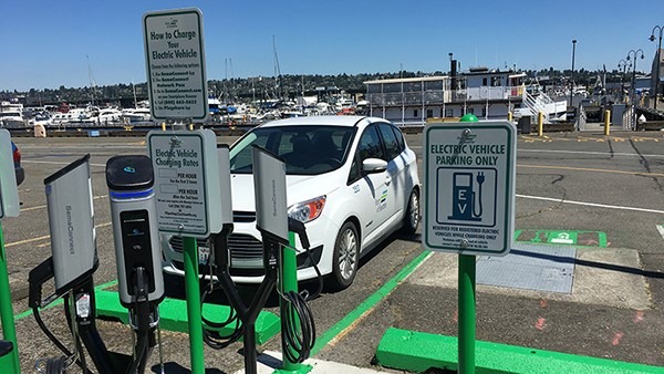 White car in parking spot  behind electric charging equipment