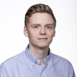 Headshot of Kristofer Mani Jonasson wearing blue striped shirt against white background